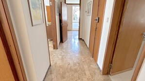 A hallway with wooden doors and marble flooring. - Prioli First Floor Flexrent Abyssinia (Riccione)