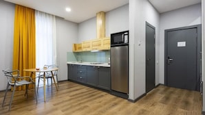 Cocina compacta con refrigerador, microondas y armarios de madera.