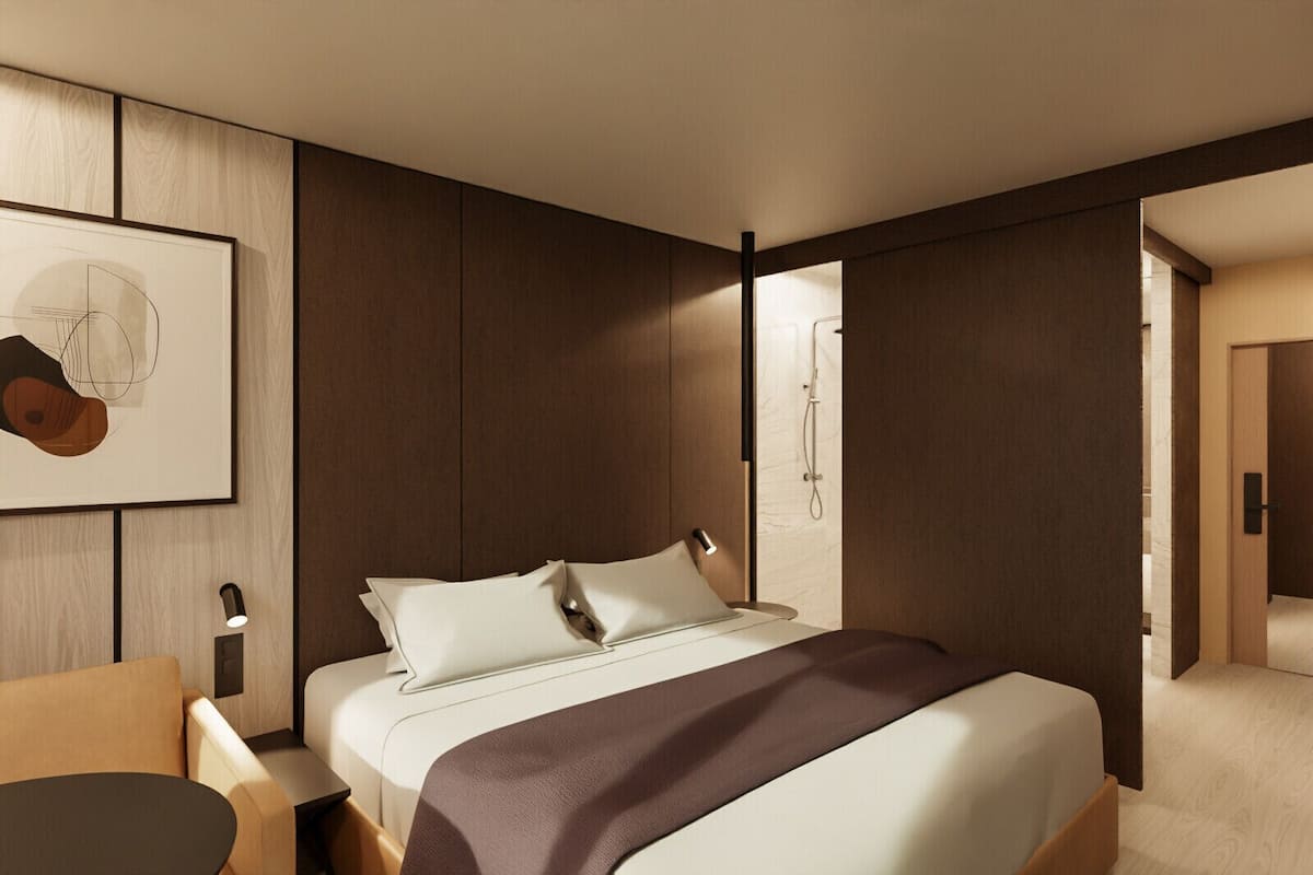 A modern hotel room with a large bed, bedside tables, a desk, and a shower area.
