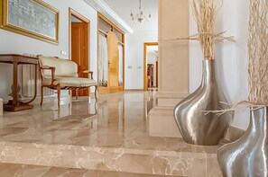 A spacious lobby with a marble floor, a sofa, a wooden cabinet, and two metallic vases with branches. - Luxurious traditional Mallorcan 4-bedroom village villa (Santa Margarida)