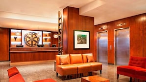 A lobby with a reception desk, a sofa, a red chair, and an elevator.