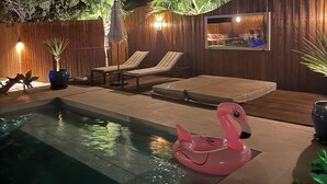 Ein Schwimmbecken mit Liegestühlen und einem Flamingo-Schwimmding.