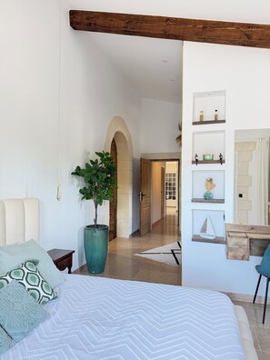 A bedroom with a large bed, a potted plant, and a wooden ceiling beam. - Villa TYMA, var Vidauban heated pool, spa house 12 persons (Vidauban)