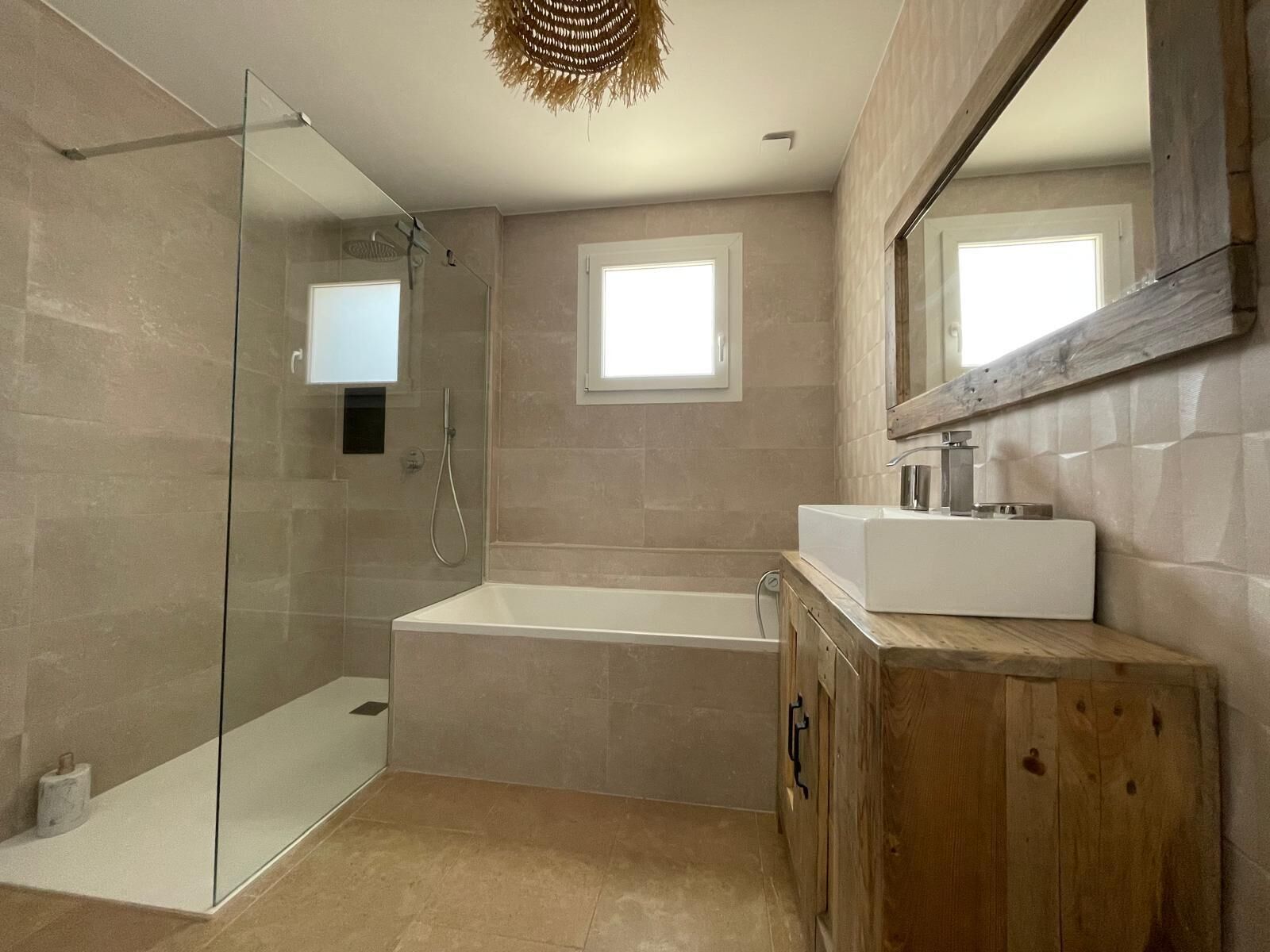 A modern bathroom with a glass shower enclosure, a freestanding bathtub, and a wooden vanity with a mirror.