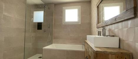 A modern bathroom with a glass shower enclosure, a freestanding bathtub, and a wooden vanity with a mirror.