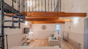 Un amplio salón con techo alto de madera, un sofá blanco y una televisión.