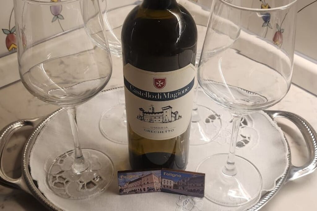 Una bottiglia di vino Grechetto dell'Umbria, Castello di Magione, con due bicchieri vuoti su un vassoio.