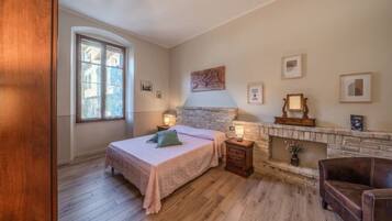 A bedroom with a bed, bedside tables, a fireplace, and a window.