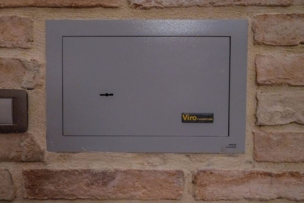 A grey electrical box with a label reading "Viro CAMICURA" mounted on a stone wall.