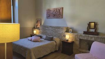 A bedroom with a bed, bedside tables, a fireplace, and a painting on the wall.