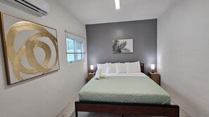 A bedroom with a bed, a nightstand, a wall-mounted air conditioner, and a window with blinds. - F. Lauderdale Near Casino & Beach 3 Bedroom House (Fort Lauderdale)
