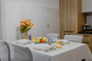 Ein Esstisch für zwei Personen, gedeckt mit Geschirr, Besteck und einer Blumenvase.