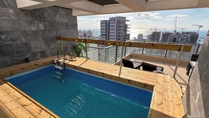 A rooftop pool with a wooden deck and a view of the city skyline. - Sky26 Mini penthouse with 6-Rooms Sew View Bat Yam (Bat Yam)