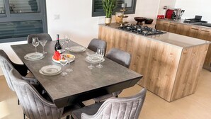 A modern kitchen with a central island, grey upholstered chairs, and a dining table set for six. - Sky26 Mini penthouse with 6-Rooms Sew View Bat Yam (Bat Yam)