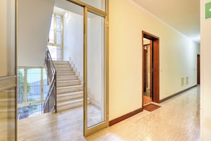 Ein geräumiger Flur mit Marmorboden, einer Treppe mit Glastüren und einer Holztür zu einem anderen Raum.