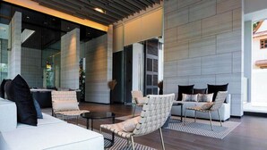 Eine moderne Lobby mit hoher Decke, großen Fenstern und einer Sitzecke mit Sofas und Sesseln.