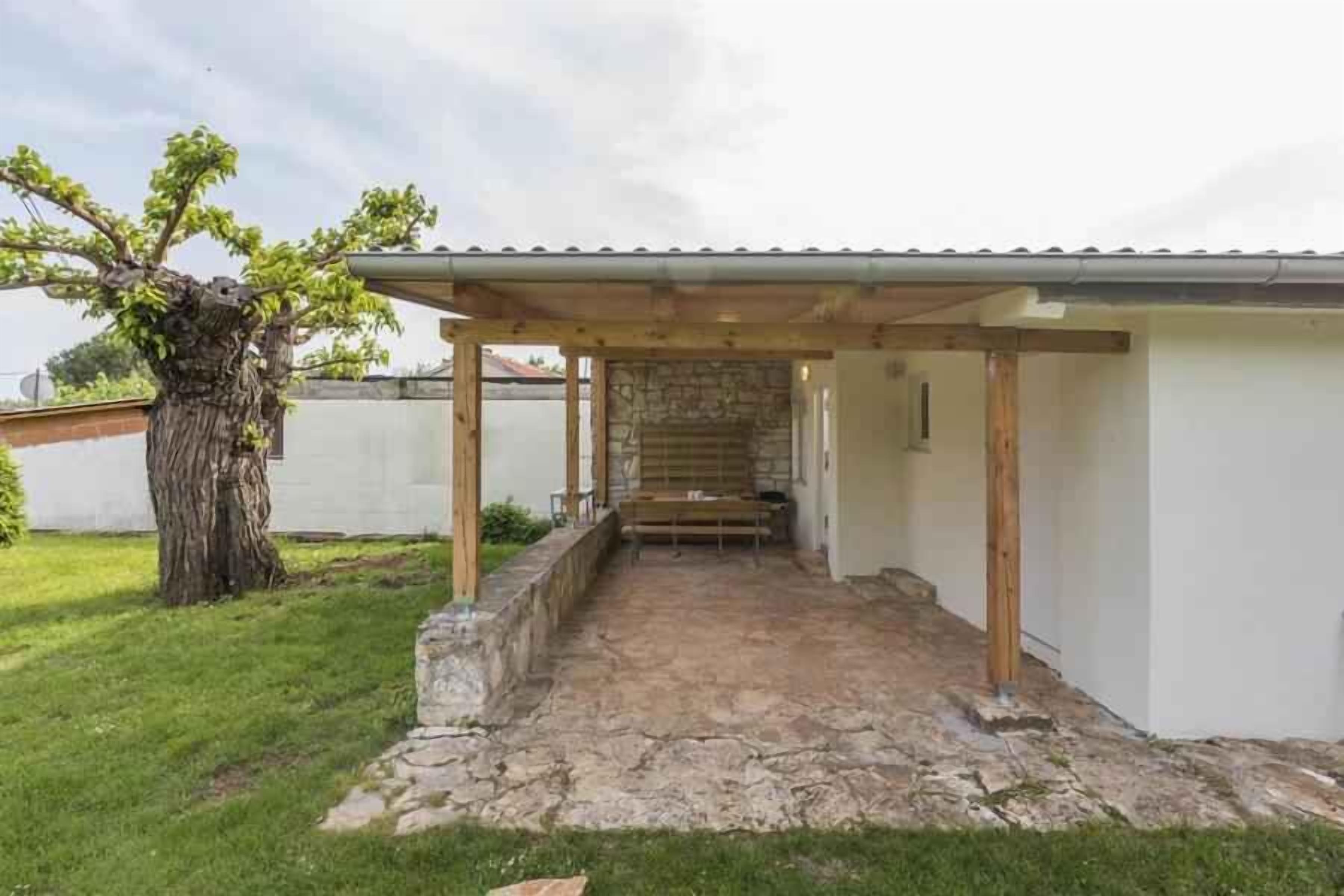 A covered patio area with a stone floor leading to a wooden door.
