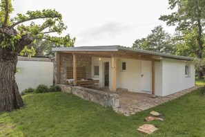 Ein kleines, eingeschossiges Gebäude mit Naturstein-Fassade und einer überdachten Veranda.