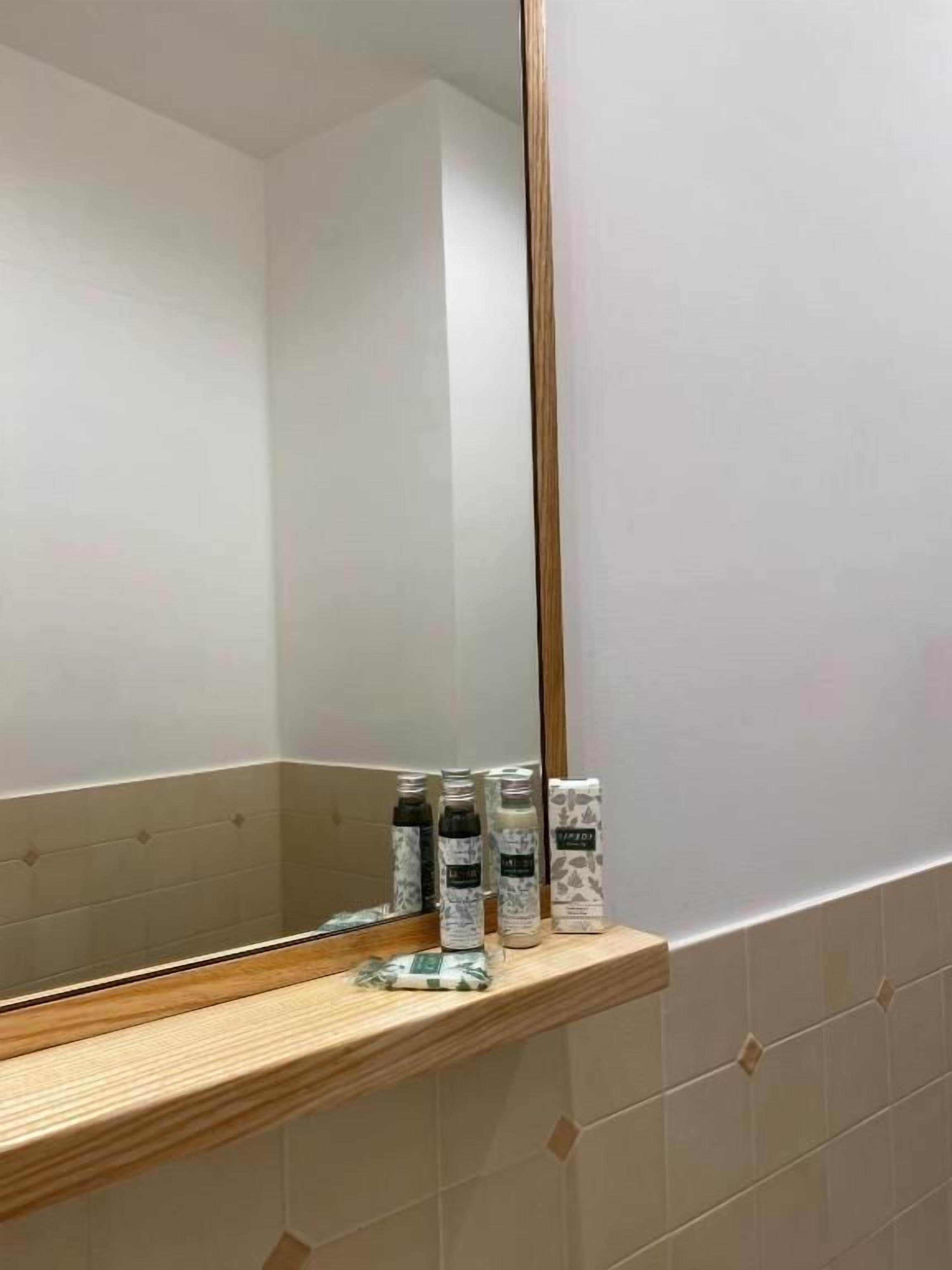 Et badeværelse med en trækommode, et spejl og toiletartikler på hylden.
