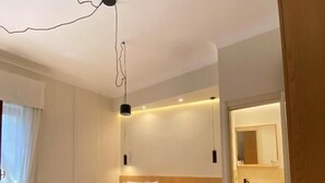 Un dormitorio moderno con una cama de madera, una mesita de noche y un banco empotrado. Hay un espejo grande sobre el banco y una lámpara del techo.
