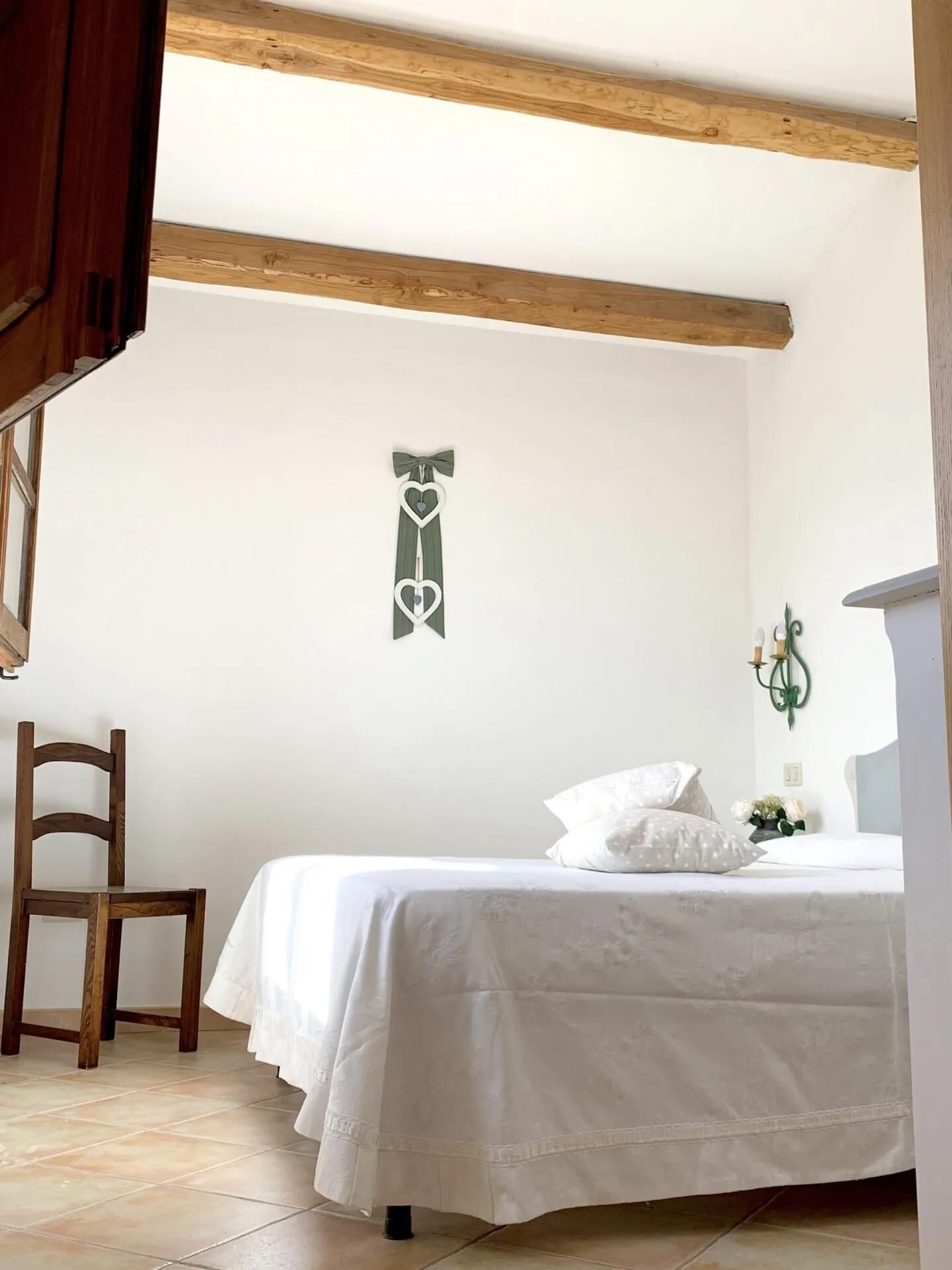 Une chambre à coucher avec un lit, une chaise, un élément de décoration murale et une fenêtre.