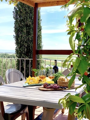 An outdoor dining area with a table set for two, featuring a bottle of wine, glasses, bread, and fruits. - Dimora le Galere - Pool&Relax (Ponti di Badia)
