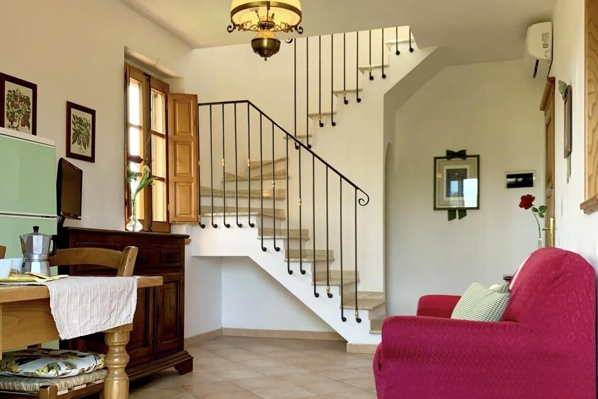 Un vaste espace de vie comprenant un escalier, une table à manger avec des chaises et un canapé rouge.