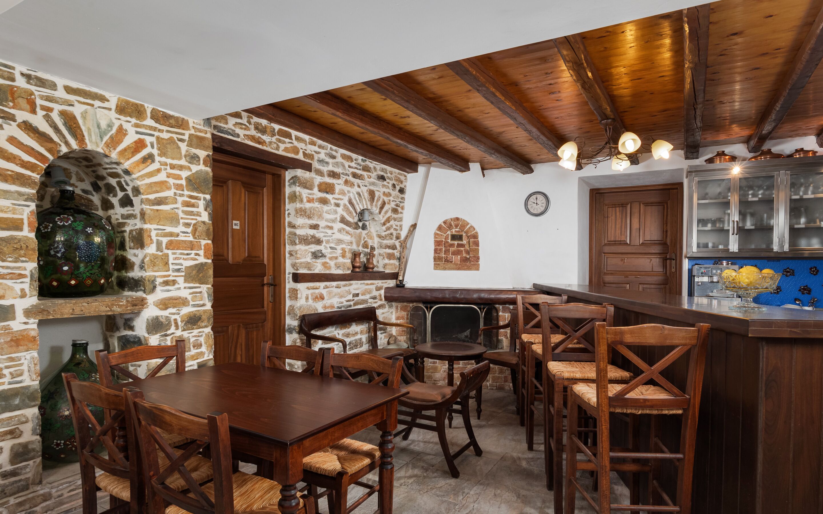 Un comedor rústico con muebles de madera, pared de piedra y techo de madera.