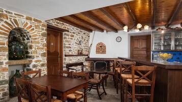 Un comedor rústico con muebles de madera, pared de piedra y techo de madera.