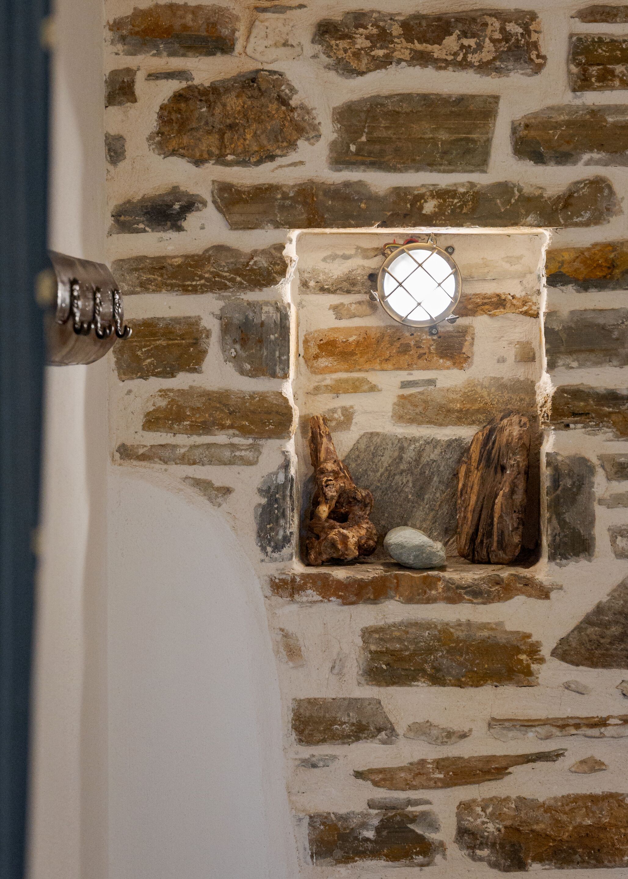 A stone wall with a small window and a metal handle.
