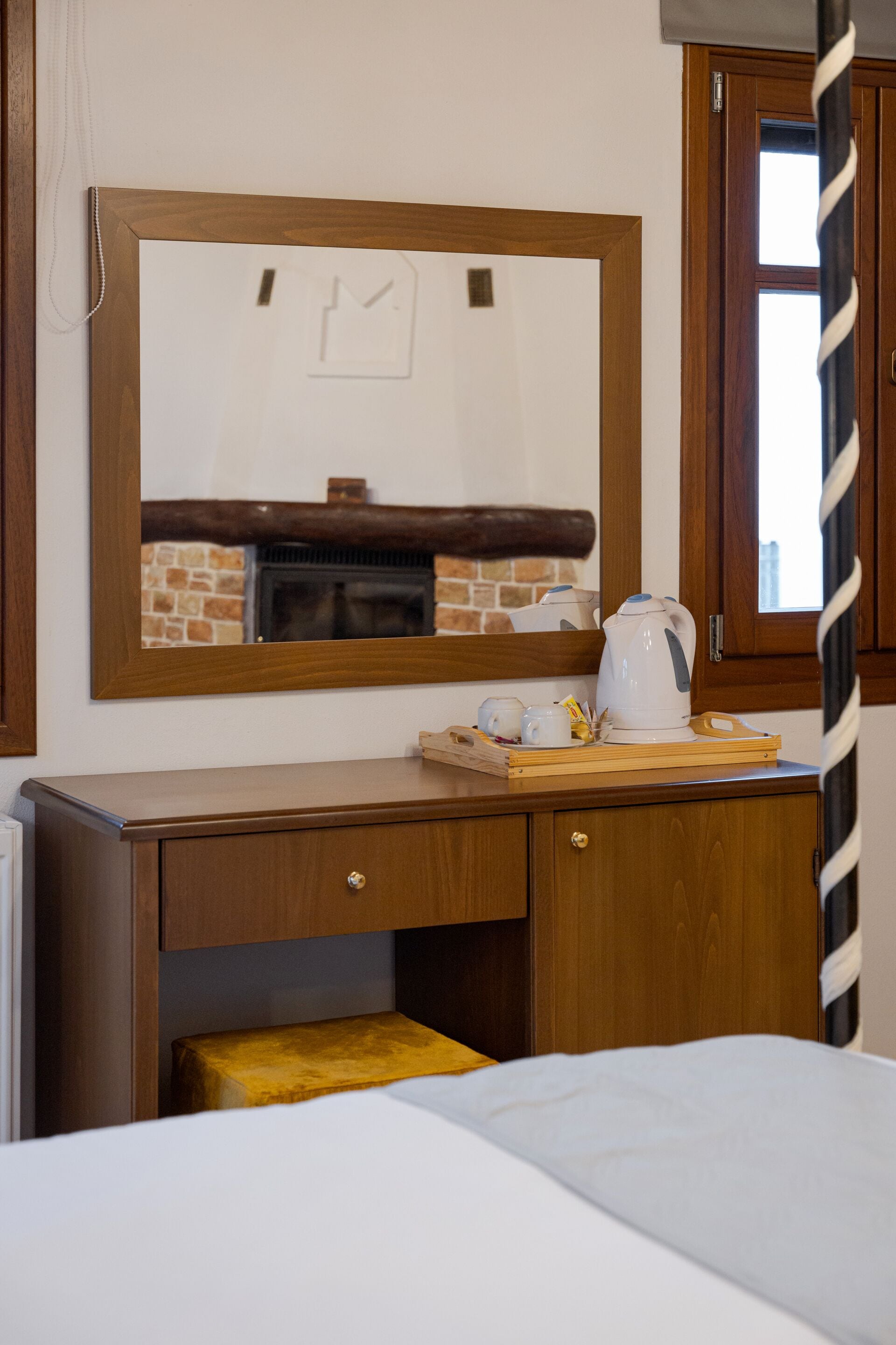 A wooden desk with a mirror above it, a kettle, and a tray with cups and a teapot.