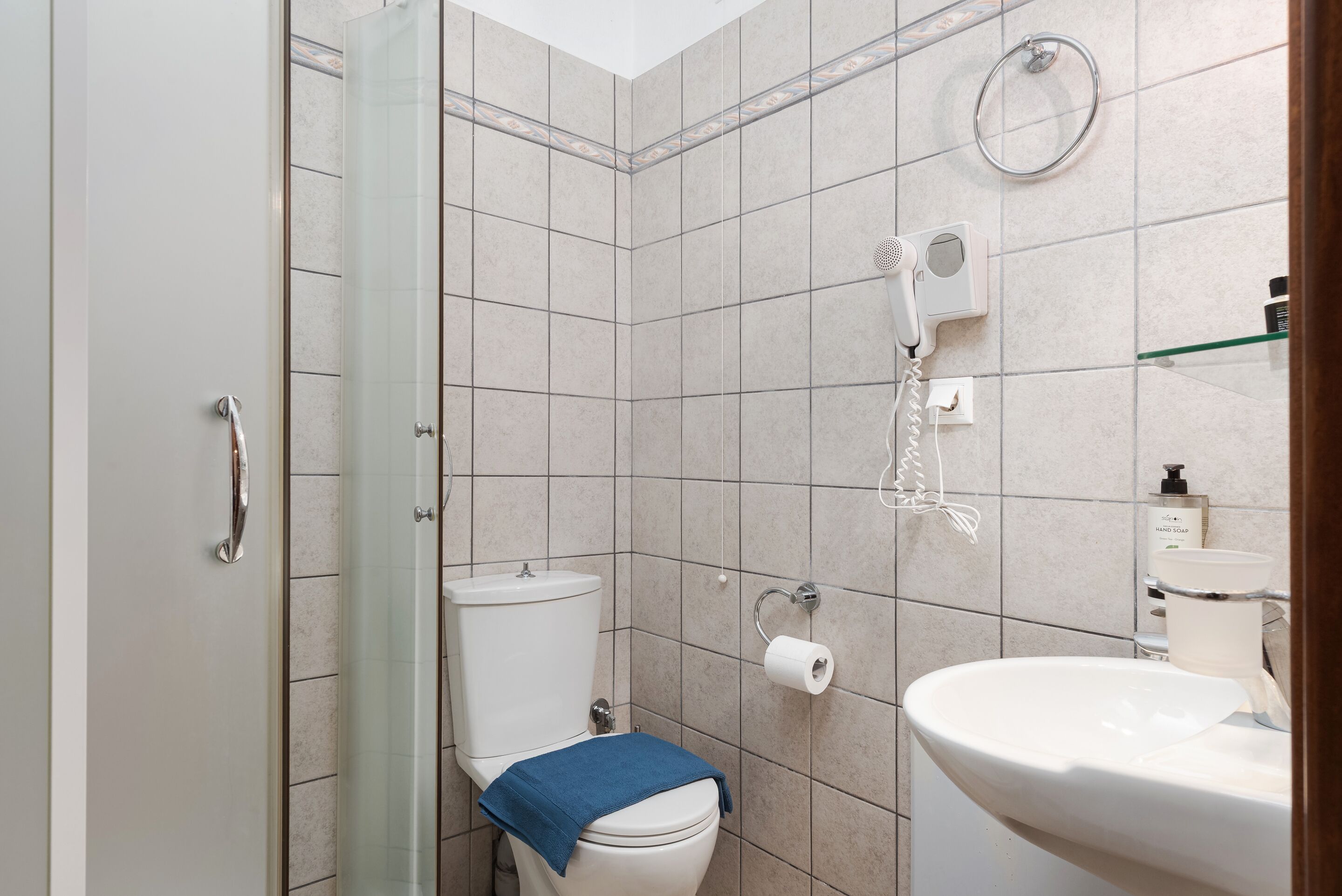 Et badeværelse med bruser, toilet og vask.