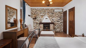 Une pièce chaleureuse avec un mur en pierre, une cheminée, des meubles en bois et un lit.