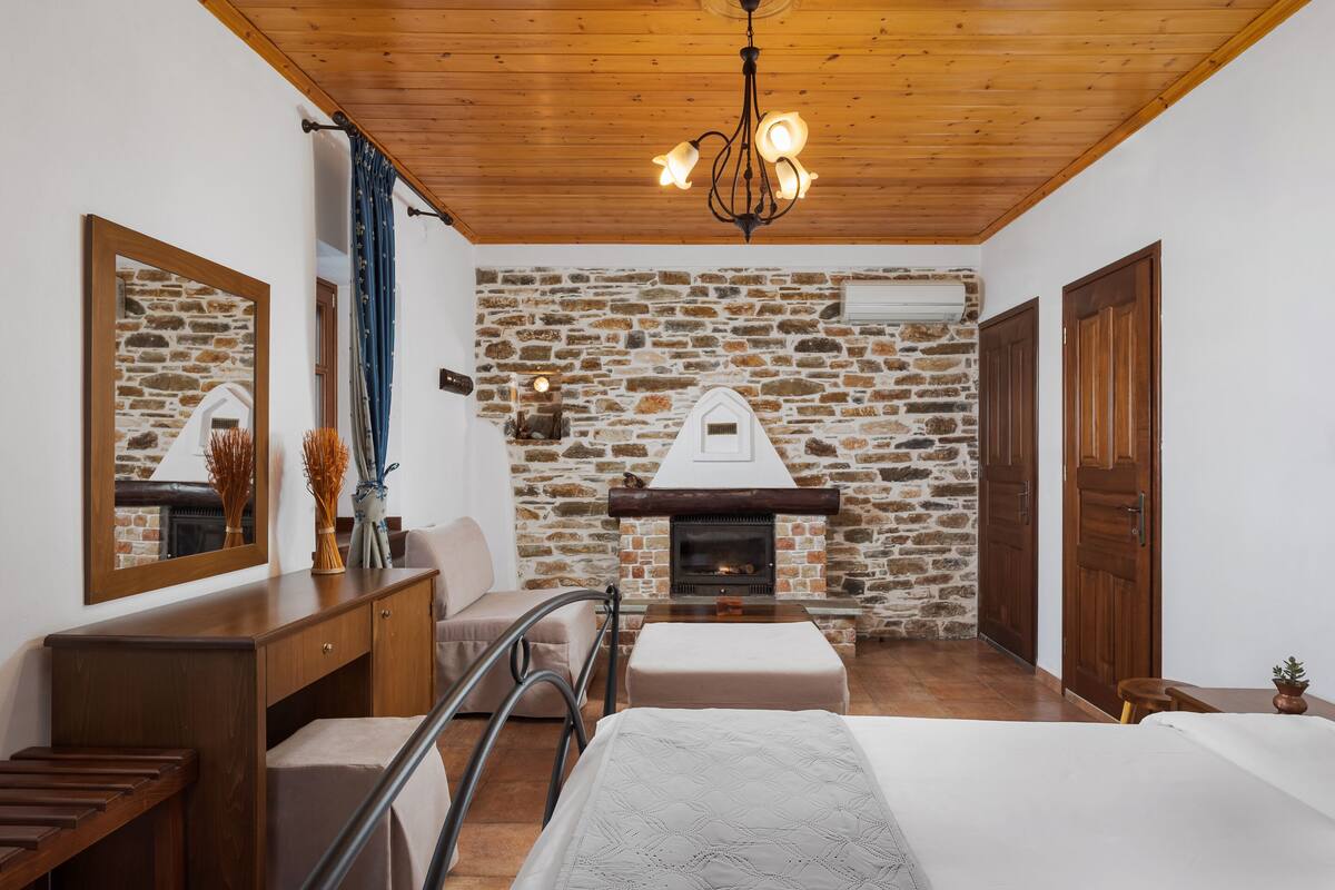 Ein gemütliches Zimmer mit Steinwand, Kamin, Holzmöbeln und einem Bett.
