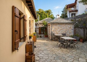 A courtyard with stone flooring, wooden furniture, and potted plants. - Archontiko Papoutsi Pelion (Mouresi)