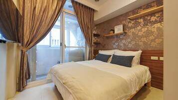 A bedroom with a bed, curtains, a window, and a wall with a floral pattern.
