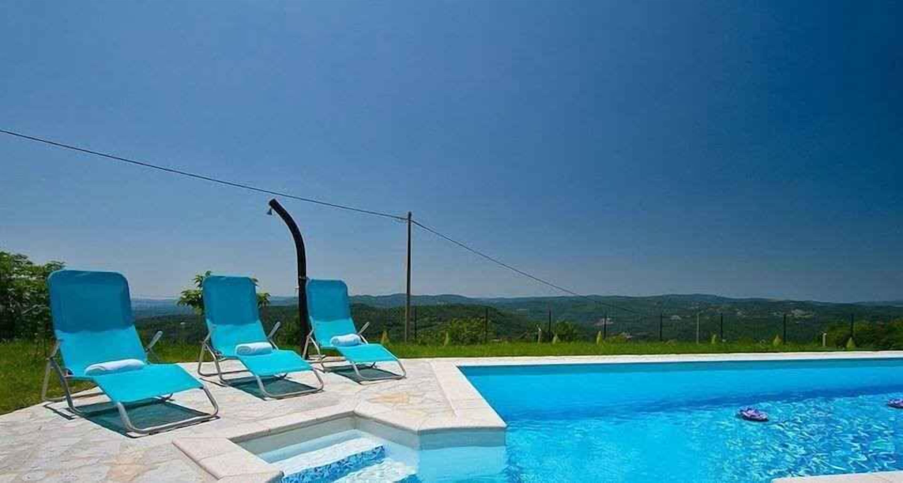 Uma área à beira da piscina com espreguiçadeiras e uma vista ampla da paisagem.