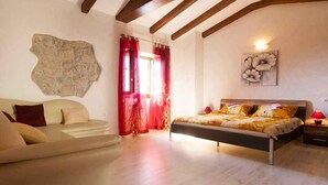 Une chambre avec un lit, un canapé, un mur en pierre et un tableau.