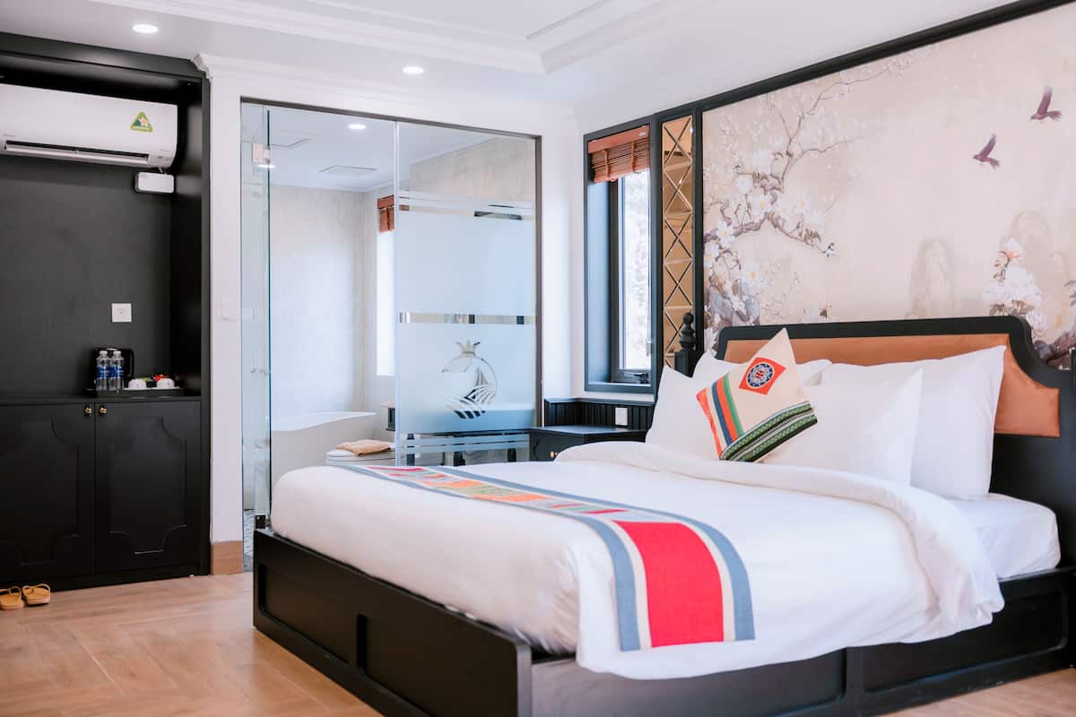 Una habitación de hotel con una cama grande, un armario, un escritorio y un espejo.