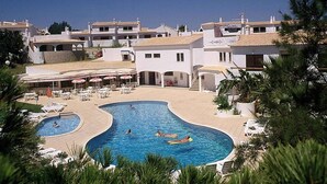 Een resort met een groot zwembadgedeelte, buitenzitplaatsen en vrij uitzicht op de omliggende gebouwen.