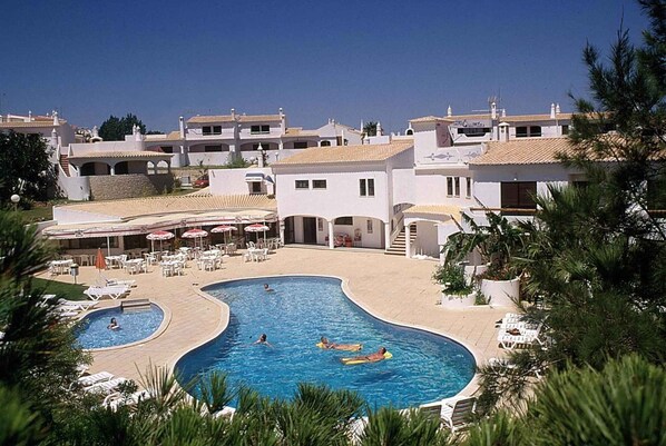 A resort with a large pool area, outdoor seating, and a clear view of the surrounding buildings. - Villa with air conditioning, balcony and pool (Porches)