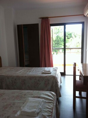A room with two beds, a desk, and a sliding glass door leading to an outdoor area. - Villa with air conditioning, balcony and pool (Porches)