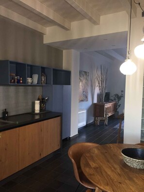 A modern kitchen with dark tiles, wooden cabinets, and a black countertop. There is a dining area with a wooden table and chairs. - Holiday apartment with air conditioning, internet and terrace (Castellabate)