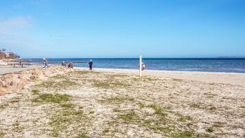 Una playa con terreno rocoso, una torre de salvavidas y un cielo azul despejado.