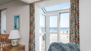 Una habitación con vistas a la playa, una silla, una lámpara y una pequeña mesa.