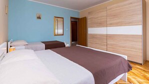 Ein Schlafzimmer mit zwei Betten, einem Kleiderschrank und einer Tür zu einem weiteren Raum.
