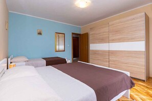 A bedroom with two beds, a wardrobe, and a door leading to another room. - Holiday apartment with air conditioning (Funtana)