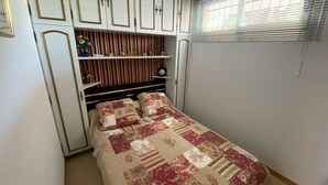 Une chambre à coucher avec un lit, une armoire et une fenêtre équipée de stores.