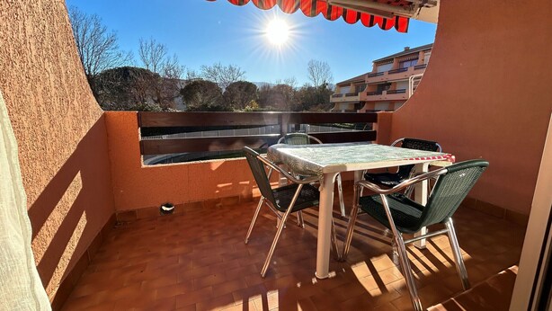 Un balcon avec une table et des chaises, une vue sur le ciel et des bâtiments en arrière-plan.