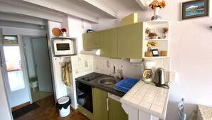Une cuisine compacte équipée d’un four à micro-ondes, d’une cuisinière, d’un évier et d’une machine à café.